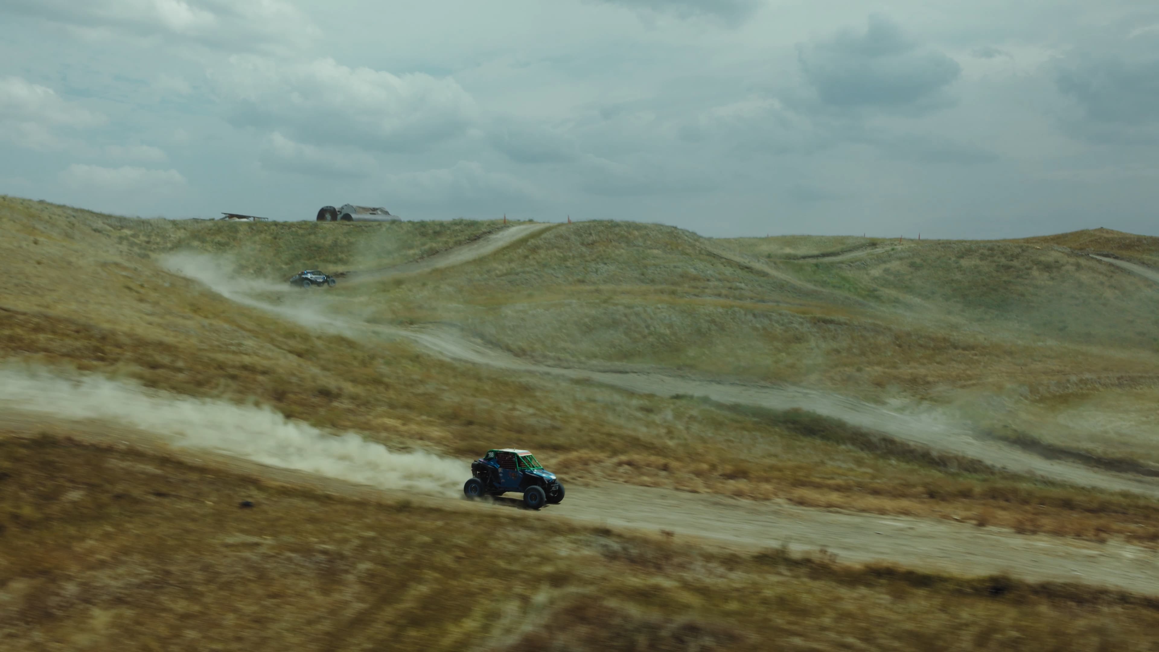 Aerial view of a race vehicle kicking up dust on a desert course.